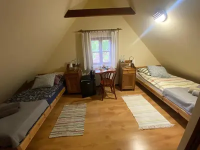 a room with two beds and a desk and a table at Karczma Siedlisko Pokoje Gościnne in Miechów