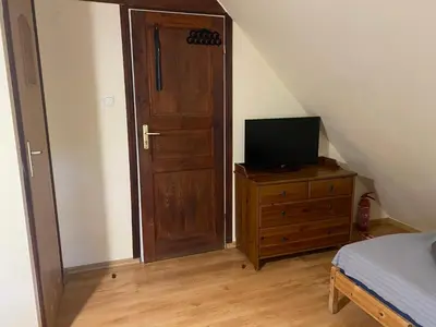 a bedroom with a wooden door and a television on a dresser at Karczma Siedlisko Pokoje Gościnne in Miechów