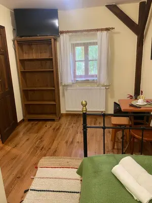 a room with a bed and a table and a window at Karczma Siedlisko Pokoje Gościnne in Miechów
