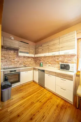 a kitchen with white cabinets and a brick wall at Osada Golców