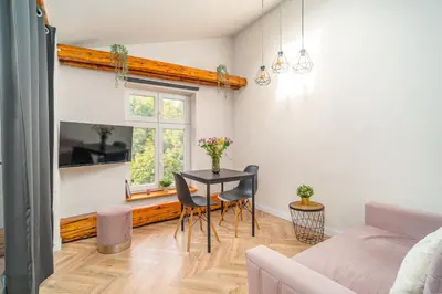 a living room with a table and a window at Old Town Siemieradzkiego Apartments by Hosty in Kraków
