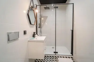 a white bathroom with a shower and a sink at Old Town Siemieradzkiego Apartments by Hosty in Kraków