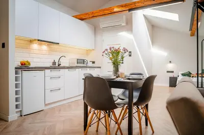 a kitchen and dining room with a table and chairs at Old Town Siemieradzkiego Apartments by Hosty in Kraków