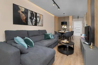 a living room with a gray couch and a table at Air Conditioned Apartment in Cracow with Parking and Desk by Noclegi Renters in Kraków