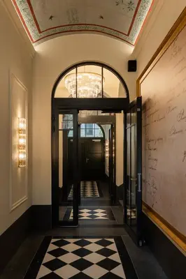 a hallway with an open door with a checkered floor at Soho Residence Kraków by Downtown Apartments in Kraków