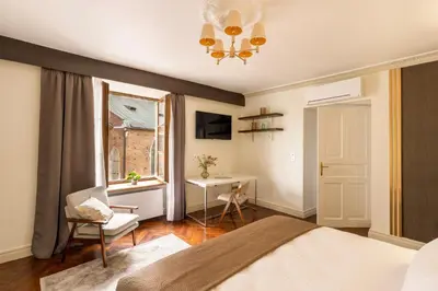 a bedroom with a bed and a desk and a window at Main Square Prestige Suites by Staymoovers in Kraków