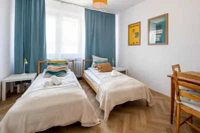 two beds in a room with blue curtains at Spacious cental treasure in Kraków