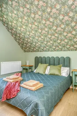 a bedroom with a blue bed with a floral wallpaper at Brzozowy Rożnów in Rożnów