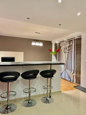 a kitchen with a bar with black stools at Modern Apartament in Kraków's Urban District in Kraków