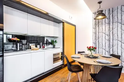 a kitchen with white cabinets and a table and chairs at ShortStayPoland Grzegórzecka C6 in Kraków