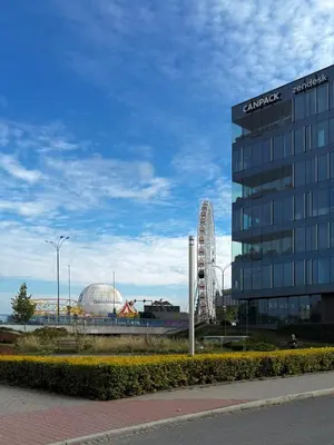 a large glass building with a ferris wheel in the background at Cozy Kraków Escape - Wawel Castle - ICE Centre in Kraków