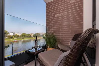 a balcony with two chairs and a table with a bottle of wine at Riva Verona Apartment 86 in Kraków