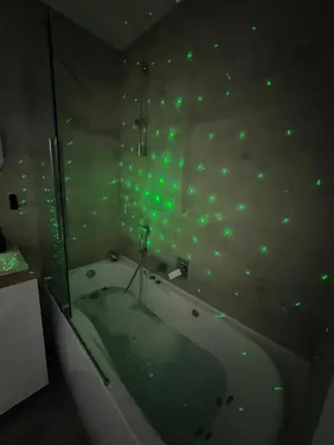 a bathroom with a tub with green lights on the wall at Zakrzówek Apartament z Jacuzzi in Kraków