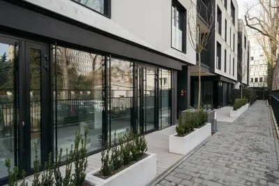 a building with glass windows and potted plants on a sidewalk at Native Apartments Kościuszki 39I14 in Kraków