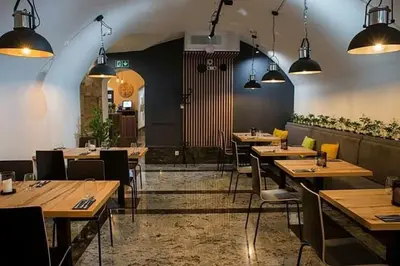 a restaurant with wooden tables and chairs and lights at Discover Krakow Apartments - 8 Rakowicka St - Stylish Balcony Apartment with Netflix in Kraków