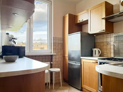 a kitchen with wooden cabinets and a large window at Cozy Two Bedrooms Apartment in Cracow City in Kraków