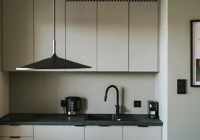 a kitchen with white cabinets and a black counter top at Rakowicka Modern Apartment with Air Conditioning in City Center by Noclegi Renters in Kraków