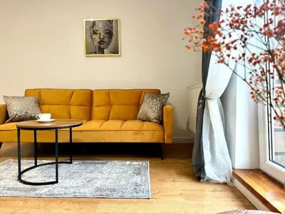 a living room with a yellow couch and a table at Apartament Zagrodowa in Oświęcim