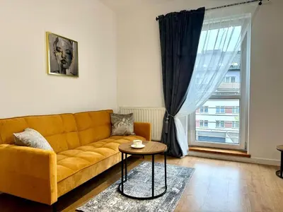 a living room with a yellow couch and a table at Apartament Zagrodowa in Oświęcim