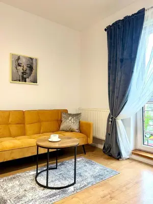 a living room with a yellow couch and a table at Apartament Zagrodowa in Oświęcim