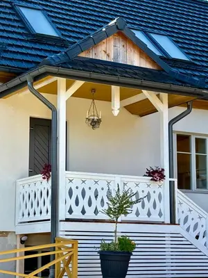 a white house with a porch with a potted plant at Villa Pippi in Tokarnia
