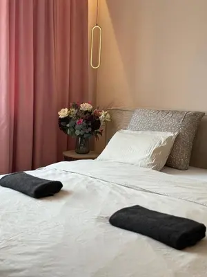 two black towels on a bed with a vase of flowers at Kraków Cozy Spot Center in Kraków