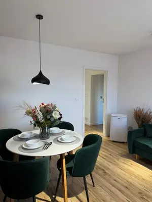 a dining room table with a vase of flowers and green chairs at Kraków Cozy Spot Center in Kraków