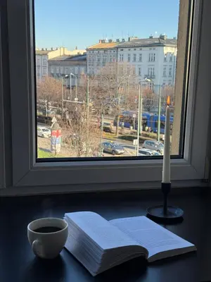 a candle and books on a table in front of a window at Kraków Cozy Spot Center in Kraków