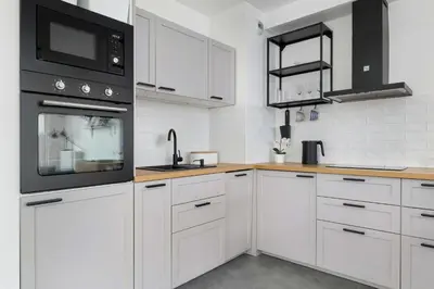 a kitchen with white cabinets and black appliances at Functional Apartment with Parking in Cracow by Noclegi Renters in Kraków