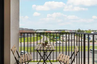 a table and chairs on a balcony with a view of a street at Functional Apartment with Parking in Cracow by Noclegi Renters in Kraków