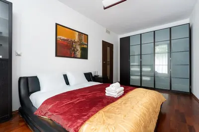 a bedroom with a large bed with a red blanket at Cracow Home Harmony Apartment by BookingHost in Kraków