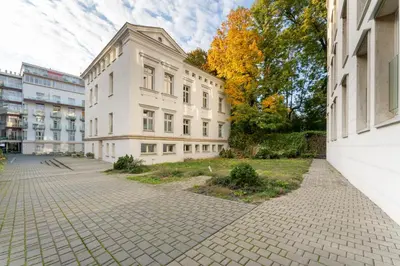 a large white building on a brick street at Cracow Home Harmony Apartment by BookingHost in Kraków