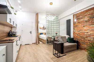 a kitchen and living room with a brick wall at Charming Kazimierz Studio near Wawel in Kraków