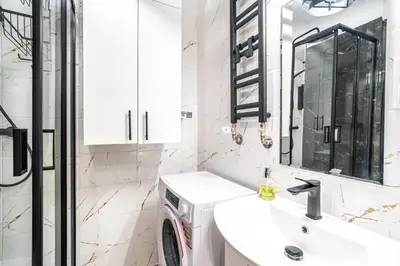 a white bathroom with a sink and a washing machine at Charming Kazimierz Studio near Wawel in Kraków
