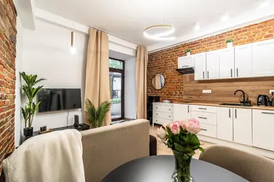 a kitchen with white cabinets and a table with flowers on it at Charming Kazimierz Studio near Wawel in Kraków