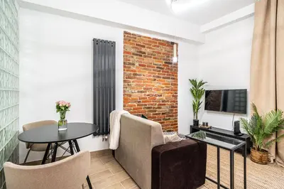 a living room with a table and chairs and a brick wall at Charming Kazimierz Studio near Wawel in Kraków