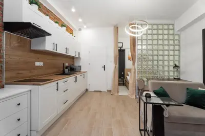 a kitchen with white cabinets and a couch at Charming Kazimierz Studio near Wawel in Kraków