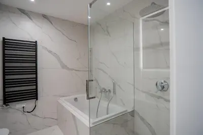 a white bathroom with a shower and a tub at K16 Apartments in Kraków