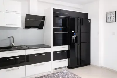 a kitchen with a black refrigerator and white cabinets at Dworek pod Jeżową Wodą in Młyńczyska