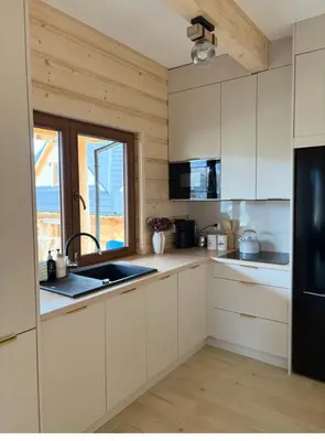 a kitchen with white cabinets and a sink and a window at Zawojenka in Zawoja