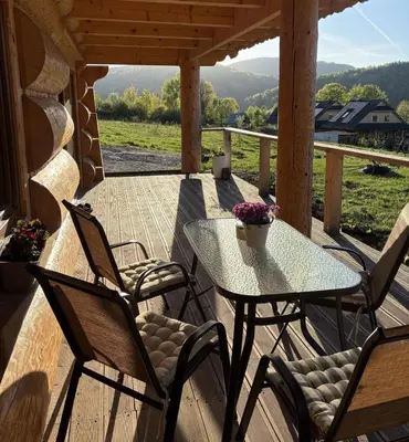 a patio with a table and chairs on a porch at Zawojenka in Zawoja