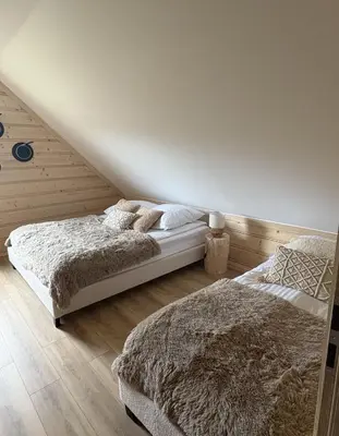 two beds in a bedroom with wooden walls at Zawojenka in Zawoja