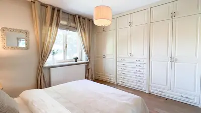 a bedroom with white cabinets and a window at Golden Villas - Elegant Family Villa with Garden near Krakow in Węgrzce