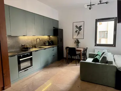 a kitchen with blue cabinets and a couch and a table at Apartament KRAKÓW CENTRUM Smoleńsk 33 in Kraków
