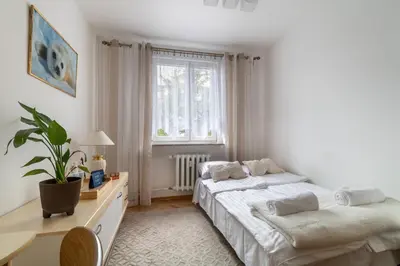 a white bedroom with two beds and a window at Malila Premium Apartments Brodowicza 5 in Kraków