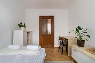a room with two beds and a desk and a table at Malila Premium Apartments Brodowicza 5 in Kraków