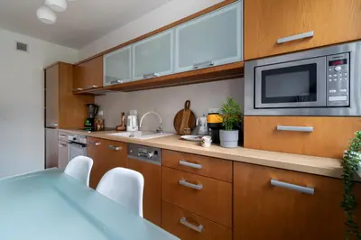 a kitchen with wooden cabinets and a microwave at Malila Premium Apartments Brodowicza 5 in Kraków