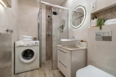 a bathroom with a washing machine and a sink at Malila Premium Apartments Brodowicza 5 in Kraków