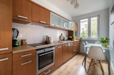 a kitchen with wooden cabinets and a table in it at Malila Premium Apartments Brodowicza 5 in Kraków