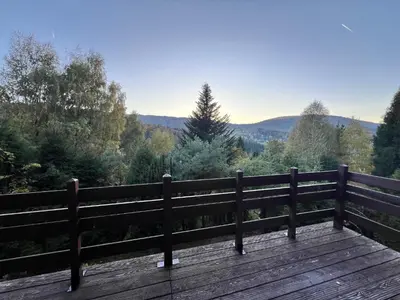 a wooden bench on a wooden deck with a view at Świerkowa Chata in Targanice